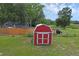 Backyard view featuring a red shed on a grassy lawn with blue home in the background at 8634 Garden Way Rd, Groveland, FL 34736