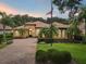 Beautiful exterior view of home with mature palm trees, manicured lawn, and brick driveway at 9433 San Miguel, Howey In The Hills, FL 34737
