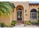 Inviting front entrance with an arched doorway, lush plants, and a beautifully landscaped walkway at 9433 San Miguel, Howey In The Hills, FL 34737