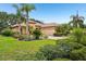 Lovely home featuring lush landscaping, mature palm trees, and a well-manicured lawn at 9433 San Miguel, Howey In The Hills, FL 34737