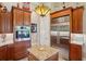 Well-equipped kitchen with stainless steel refrigerator, built-in oven, and granite island with custom wood cabinetry at 9433 San Miguel, Howey In The Hills, FL 34737