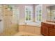 Luxurious main bathroom with a glass-enclosed shower, soaking tub, and abundant natural light streaming through shuttered windows at 9433 San Miguel, Howey In The Hills, FL 34737