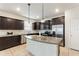 Well-lit kitchen boasts stainless appliances, dark cabinetry, light granite, tile floor and a large island at 120 Citrus Isle St, Davenport, FL 33837