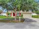 Charming single-story home featuring a red front door, red shutters, well-manicured landscaping, and a spacious two-car garage at 1216 Cheshire St, Groveland, FL 34736