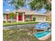 Charming single-story home featuring a red front door, red shutters, well-manicured landscaping, and a beautiful pool at 1216 Cheshire St, Groveland, FL 34736