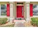 Inviting front entrance featuring a vibrant red door, neutral columns, and decorative stone landscaping at 1216 Cheshire St, Groveland, FL 34736