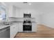 Updated kitchen with stainless steel appliances, granite counters, and white cabinets and wood flooring at 1421 E Schwartz Blvd, The Villages, FL 32159