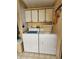 Practical laundry area equipped with a washer, dryer, and overhead storage cabinets at 163 Sweet Cir, Winter Haven, FL 33884