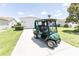 Driveway scene of a golf cart at a charming home with a manicured lawn and beautiful landscaping at 1654 Blossom Ter, The Villages, FL 32162