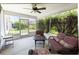 Inviting screened porch with garden view, a ceiling fan and comfortable wicker furniture set at 1654 Blossom Ter, The Villages, FL 32162