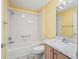 Bathroom with marble countertop vanity and shower-tub combo with white tiled walls at 1889 Union Pl, The Villages, FL 32162