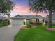 Charming single-story home boasts a well-manicured lawn, inviting curb appeal, and an attached two-car garage at 1889 Union Pl, The Villages, FL 32162