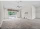 Open living room with a ceiling fan, sliding doors to sunroom, and neutral carpeting at 1889 Union Pl, The Villages, FL 32162