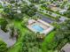 Aerial view of a community pool surrounded by palm trees, lounge chairs, and lush greenery, with parking nearby at 1889 Union Pl, The Villages, FL 32162