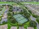 Aerial view of a community tennis court with surrounding trees and parking near a beautiful golf course at 1889 Union Pl, The Villages, FL 32162
