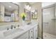 Bright bathroom with double sink vanity, framed mirrors, and a glass-enclosed shower at 2055 Merideth Ter, The Villages, FL 34762