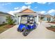 View of the home's exterior featuring a Yamaha golf cart parked in the driveway and a two car garage at 2055 Merideth Ter, The Villages, FL 34762
