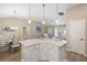 Kitchen island with white cabinets, a view of the dining area, and an adjacent sitting area at 2055 Merideth Ter, The Villages, FL 34762