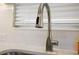 Close-up of the kitchen sink featuring a stainless steel faucet and white subway tile backsplash at 2055 Merideth Ter, The Villages, FL 34762