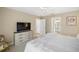 Comfortable main bedroom with white bedding, light wood dresser, and adjacent bathroom and closet at 2055 Merideth Ter, The Villages, FL 34762