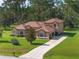 Expansive home with a long driveway, attached garage, lush green lawns, and mature trees at 21312 Marsh View Ct, Clermont, FL 34715