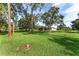Exterior view of the backyard with mature trees, green lawn, and a screened in pool at 21312 Marsh View Ct, Clermont, FL 34715