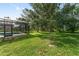 Backyard view showing a beautiful green lawn with mature trees and a screened in pool area at 21312 Marsh View Ct, Clermont, FL 34715