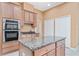 Spacious kitchen featuring an island, stainless steel oven, microwave, wood cabinets, and granite countertops at 21312 Marsh View Ct, Clermont, FL 34715