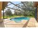 Backyard screened-in pool with a view of a treed area with manicured lawn at 21312 Marsh View Ct, Clermont, FL 34715