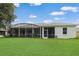 Exterior of home showing screened in back patio, green grass backyard, and lush trees in background at 22125 Draw Bridge Dr, Leesburg, FL 34748