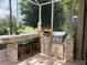 Outdoor kitchen and bar area under a screened lanai with a view of the backyard at 2299 Twickingham Ct, Clermont, FL 34711