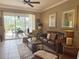 Spacious living room with leather seating, ceiling fan, and sliding glass doors to the outdoor patio at 2299 Twickingham Ct, Clermont, FL 34711