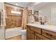 Bathroom features a shower/tub combo, vanity with wood cabinets, tan walls, and a framed mirror at 26653 Otter Creek Ln, Leesburg, FL 34748