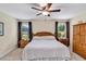 Bedroom with neutral walls, ceiling fan, two windows with dark curtains, and natural wood furniture at 26653 Otter Creek Ln, Leesburg, FL 34748