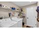 This bright laundry room features a washer, dryer, storage shelves, and convenient utility sink at 26653 Otter Creek Ln, Leesburg, FL 34748