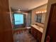 Well-lit bathroom with a glass block shower, a tiled floor, and a wooden vanity at 29205 Old E Ml, Tavares, FL 32778