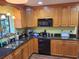 A well-lit kitchen featuring wooden cabinets, black appliances, and granite countertops at 29205 Old E Ml, Tavares, FL 32778