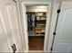 Walk-in closet featuring built-in shelving units for storage, wood floors, and decorative wallpaper at 295 Whirlaway Drive, Davenport, FL 33837