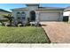 Charming single-story home with a well-manicured lawn, desert landscaping, and a brick driveway at 295 Whirlaway Drive, Davenport, FL 33837