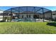 Backyard showcasing a screened-in pool and spa, set against a lush lawn and the home's exterior at 295 Whirlaway Drive, Davenport, FL 33837
