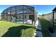 Backyard view of a screened-in pool with modern patio, framed by a green lawn and the home's exterior at 295 Whirlaway Drive, Davenport, FL 33837
