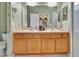 Bathroom featuring a double vanity with light wood cabinets and decorative floral wallpaper at 3507 Arlington Ridge Blvd, Leesburg, FL 34748