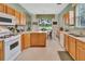 Bright kitchen featuring wood cabinets, white appliances, and a breakfast nook with natural light at 3507 Arlington Ridge Blvd, Leesburg, FL 34748