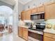 Kitchen featuring light wood cabinets, granite countertops, and modern appliances at 3601 Mount Hope Loop, Leesburg, FL 34748