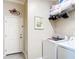 Laundry room with front loading washer and dryer, storage shelf, and a white door at 3601 Mount Hope Loop, Leesburg, FL 34748
