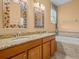 Bathroom featuring granite countertops, tile accents, dual sinks, and a large soaking tub at 3677 Serena Ln, Clermont, FL 34711