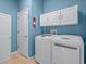 Well-organized laundry room with modern washer and dryer, built-in storage, and blue walls at 3677 Serena Ln, Clermont, FL 34711