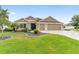 Charming one-story home featuring a well-maintained lawn, mature landscaping, and a spacious three-car garage at 3750 Raspberry Ct, The Villages, FL 32163