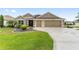 Charming one-story home featuring a well-maintained lawn, mature landscaping, and a spacious three-car garage at 3750 Raspberry Ct, The Villages, FL 32163