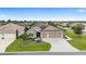 Aerial view of a well-maintained home featuring a three-car garage and lush landscaping at 3750 Raspberry Ct, The Villages, FL 32163